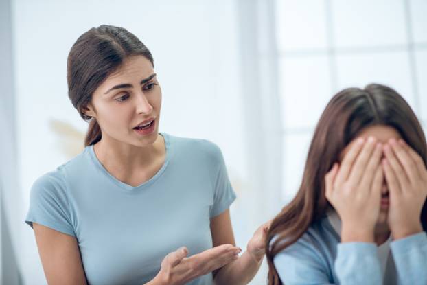 Attentive knowledgeable mother talking to turned away daughter