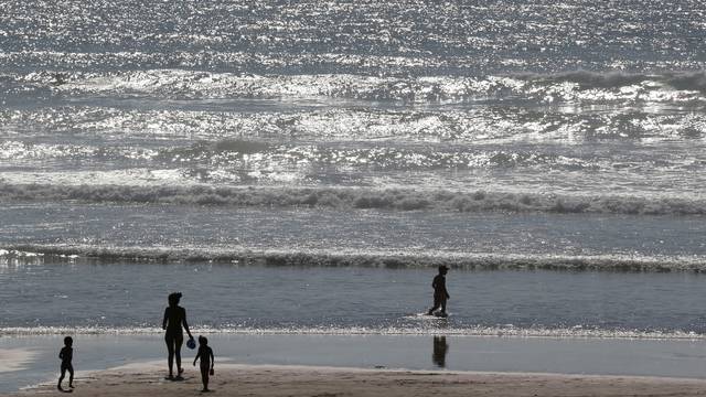 Holidays makers walk on the beach along the Atlantic Ocean as warm summer temperatures continue in Montalivet