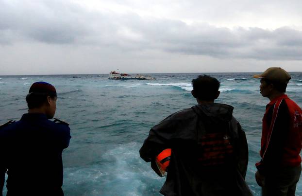 Villagers and officials stand as KM Lestari Maju boat sinks in the waters of Selayar island