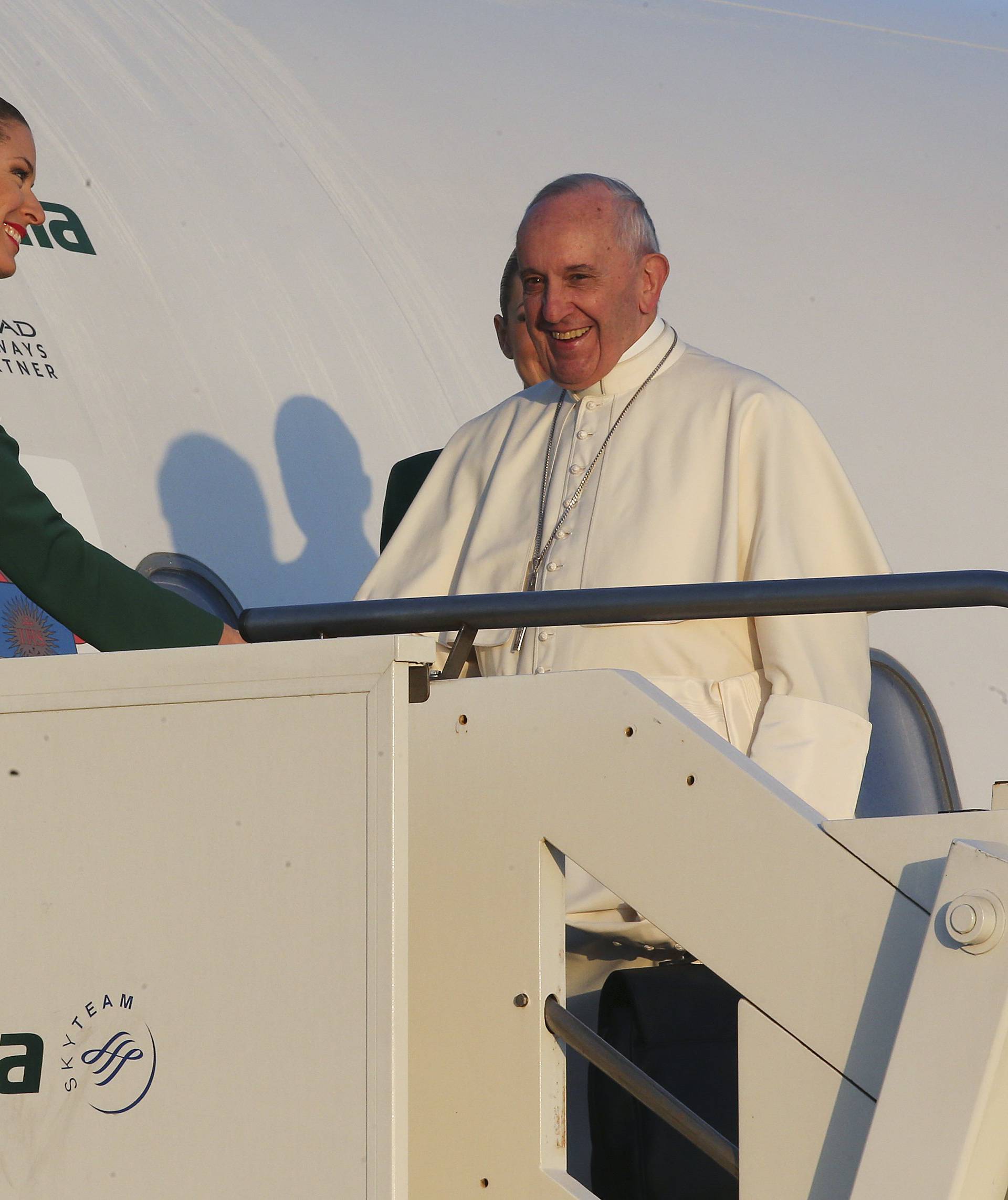 Pope Francis is greeted by a flight attendant as he boards a plane at Fiumicino Airport in Rome