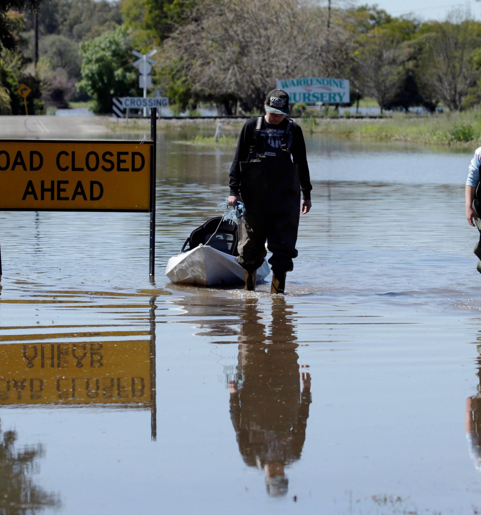 Local residents wade along a road closed due to flooding following heavy rains in the midwestern New South Wales town of Forbes