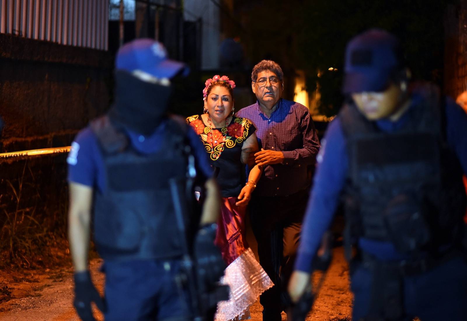 People react next to police officers guarding a crime scene where unidentified assailants opened fire at a bar in Minatitlan