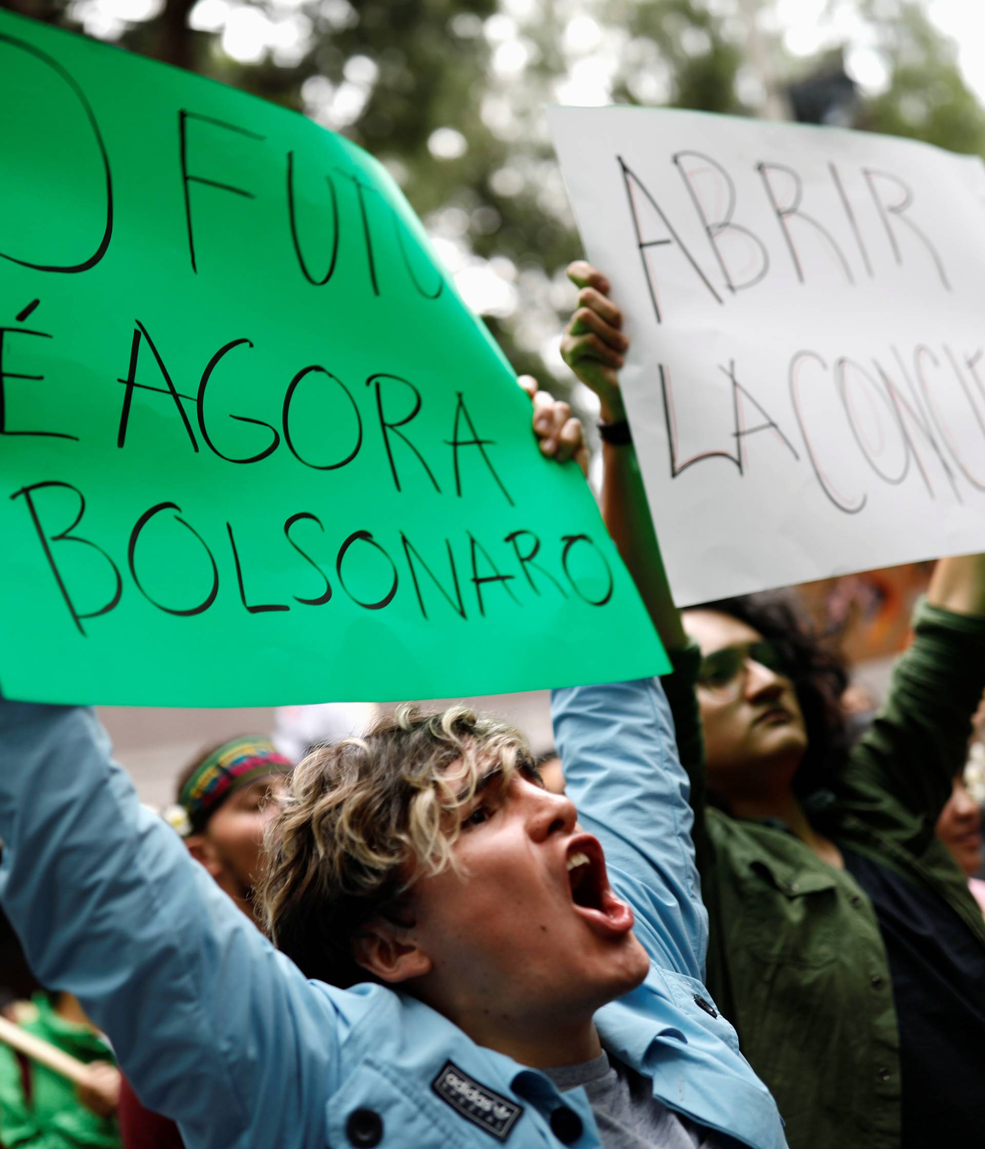 Activists hold signs during a protest to demand more Amazon rainforest protection at the embassy of Brazil in Mexico City