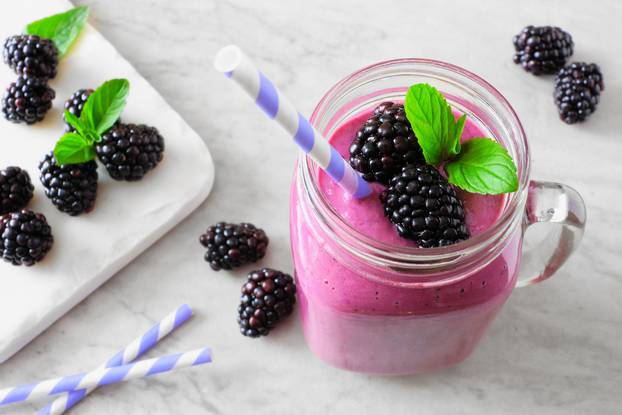 Blackberry smoothie in a mason jar, close up table scene against marble