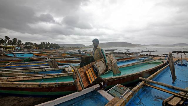 A fisherman carries his tools as he leaves for a safer place after tying his boats along the shore ahead of cyclone Fani in Peda Jalaripeta on the outskirts of Visakhapatnam