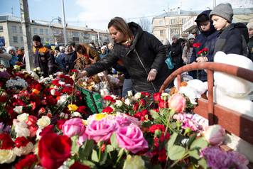 People place flowers at a makeshift memorial for the victims of a shopping mall fire in Kemerovo