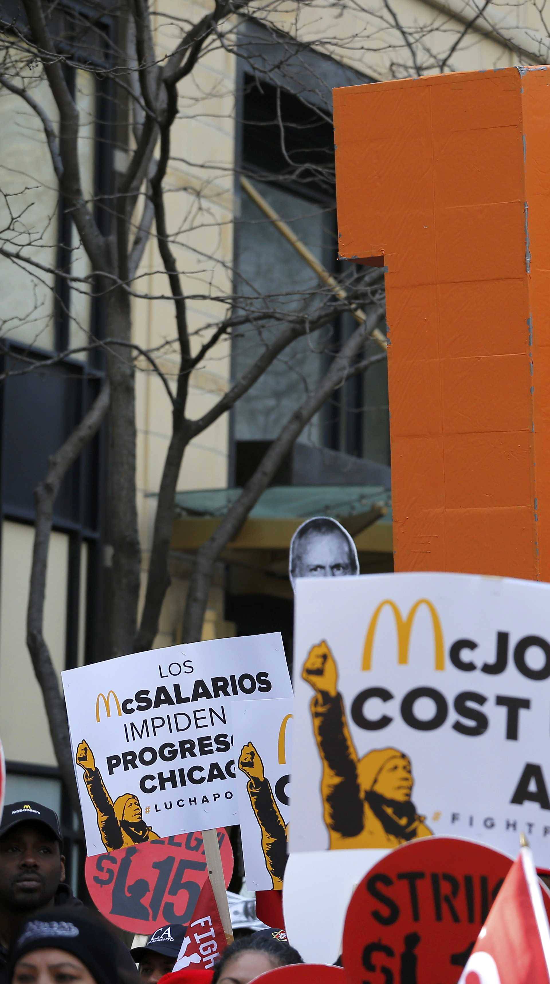 A Chicago Police officer looks on as demonstrators gather on the sidewalk with placards during a protest for a $15-an-hour nationwide minimum wage in downtown Chicago