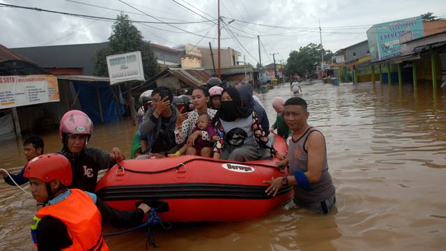 Rescue workers push an inflatable boat as they evacuate residents following floods in Makassar