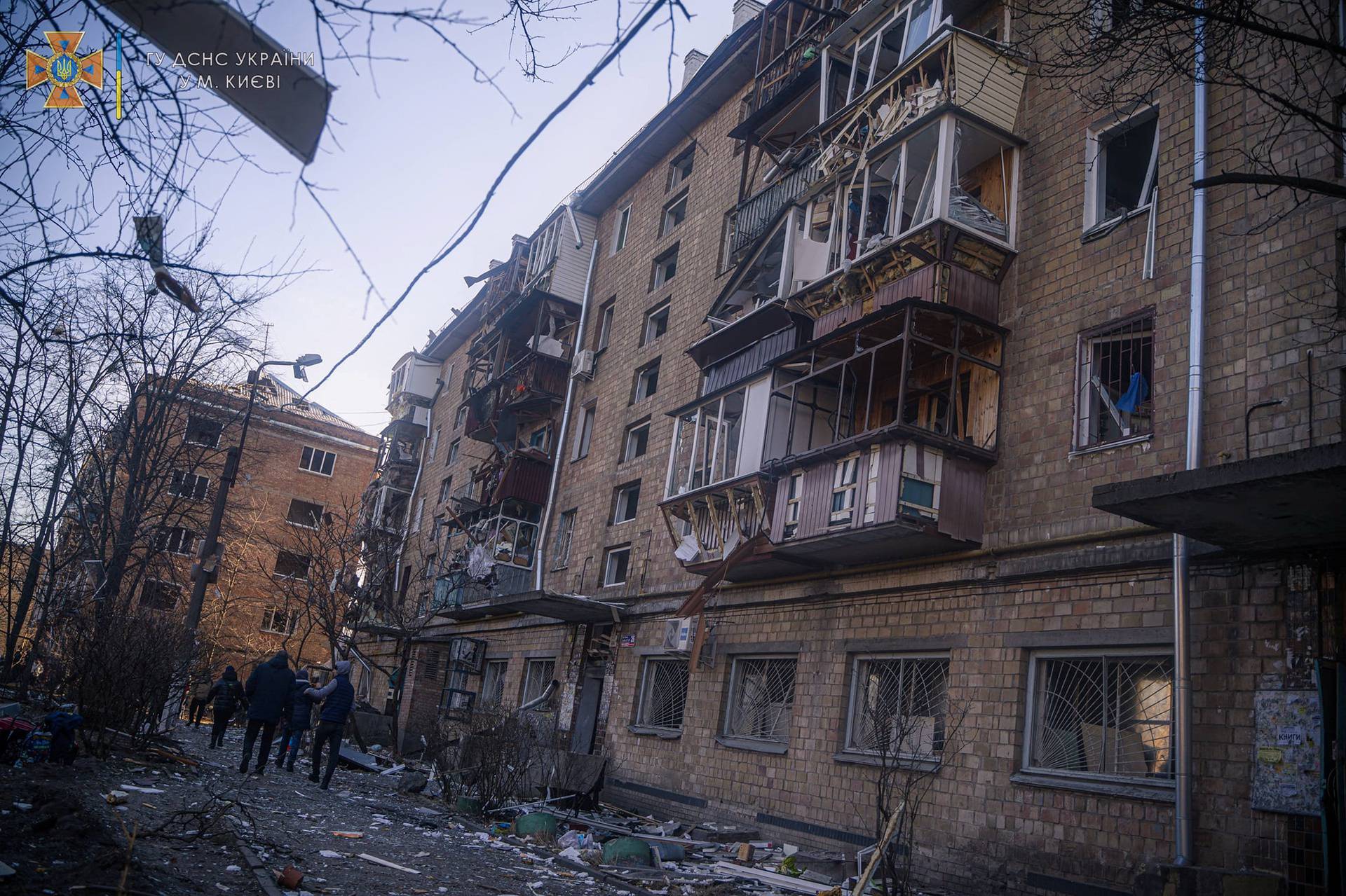Locals walk next to a residential building damaged by shelling in Kyiv