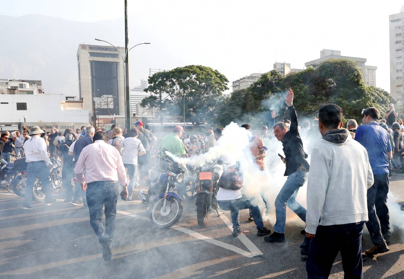 People react to tear gas near the Generalisimo Francisco de Miranda Airbase in Caracas