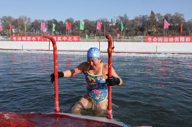 Locals participate in winter swimming events during the annual ice and snow sculpture festival, in Harbin