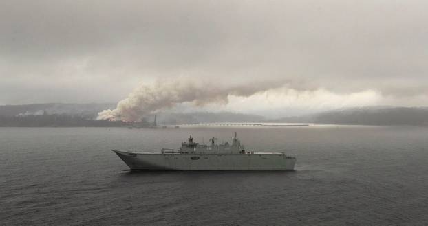 HMAS Adelaide operates off the coast of Eden, Australia, as fires burn during Operation Bushfire Assist