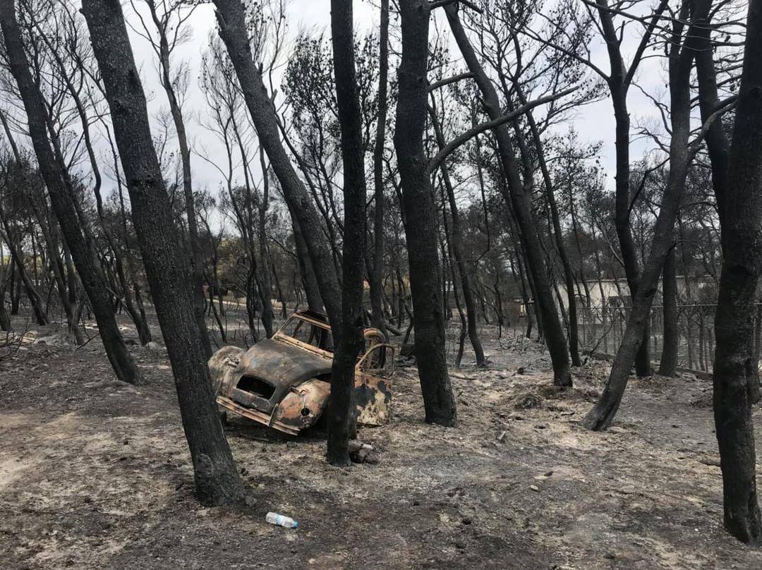 A burnt car is seen after a wildfire in Mati