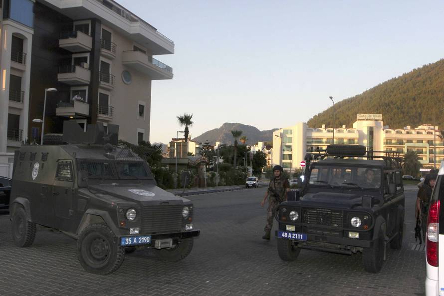 Policemen patrol the streets as two police vehicles block a road in the resort town of Marmaris