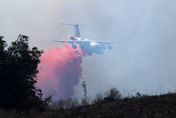 A Water bomber drops fire retardant as fire crews work to protect a Sullivan Middle School from a fast moving wild fire in Bonsall, California