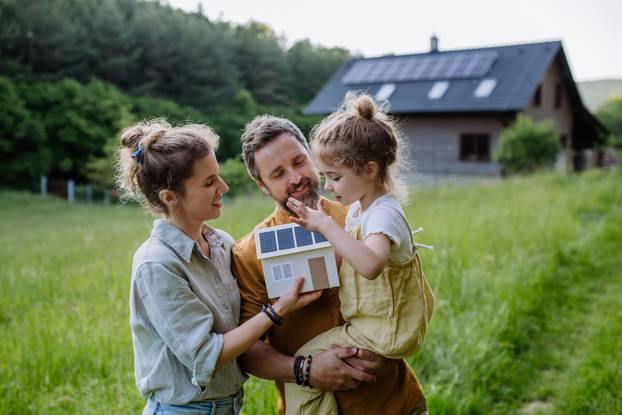 Happy,Family,In,Front,Of,Their,House,With,Solar,Panels