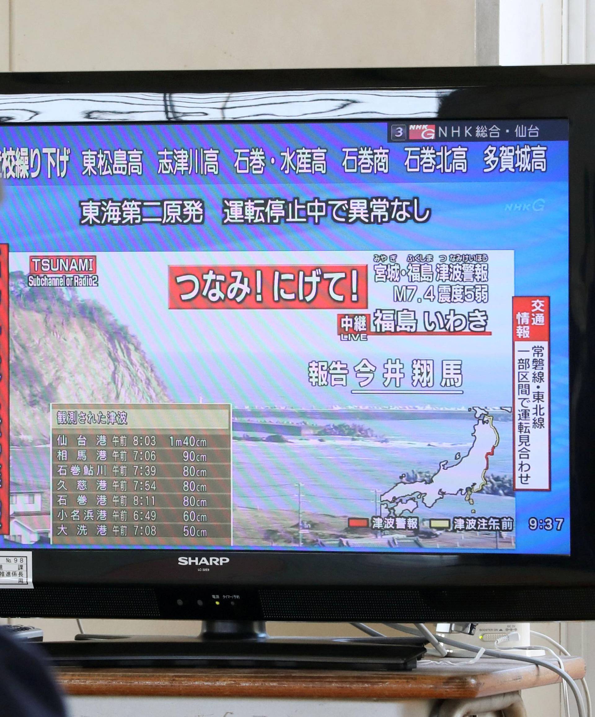 A man evacuated from his home looks at a television screen showing a news report on tsunami warnings, at a shelter following an earthquake, in Sendai