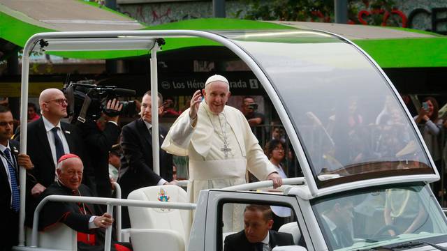 Pope Francis waves to people while driving through Santiago