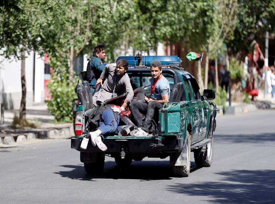 Afghan security forces carry injured men on a back of police car near the site a blast in Kabul, Afghanistan