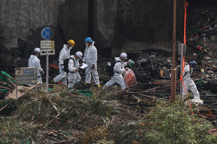 Police officers wearing protective suits collect samples at the site of a fire-damaged residential block at Wang Fuk Court housing complex in Tai Po, Hong Kong