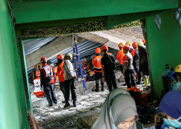 Search and rescue officers stand amidst rubble of a collapsed building at the Al-Khoziny Islamic boarding school in Sidoarjo