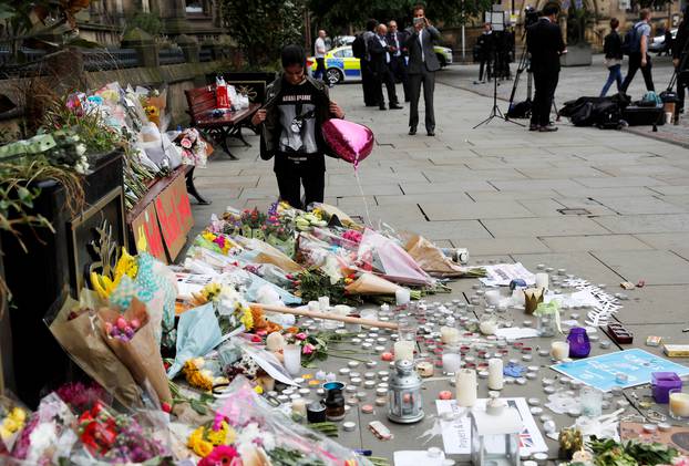 An Ariana Grande fan stands next to floral tributes left for the victims of an attack on concert goers at Manchester Arena, in St Ann