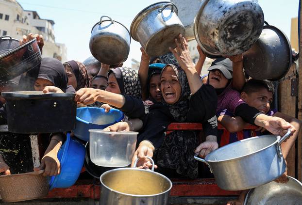 Palestinians wait to receive food from a charity kitchen, in Gaza City