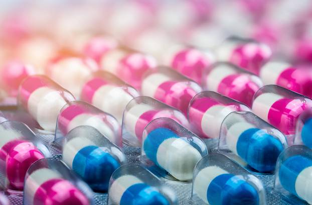 Closeup pink-white and blue-white antibiotics capsule pills in b