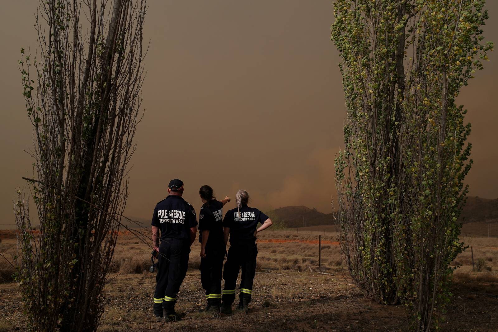 Personnel from Fire and Rescue NSW monitor a bushfire as it approaches a home in Bredbo