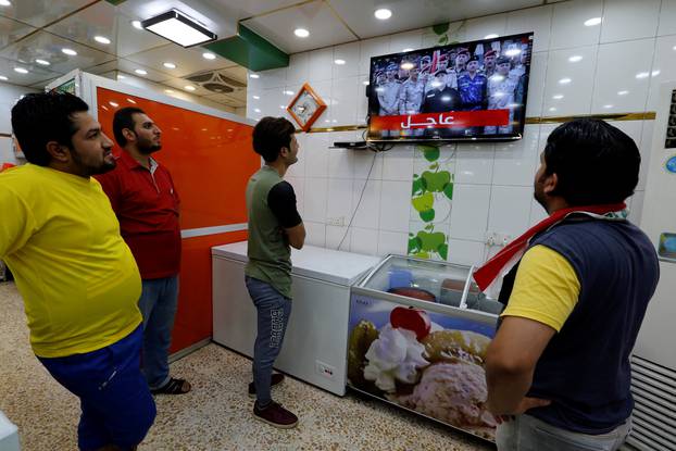 Iraqi men watch on a TV as Iraqi Prime Minister Haider al-Abadi announces victory over Islamic State, in Baghdad