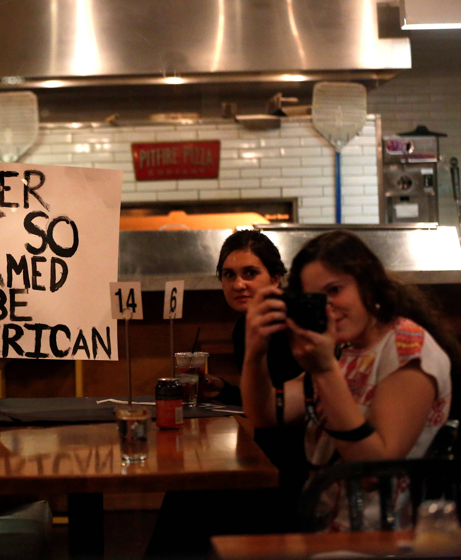 Patrons hold a sign as people march by while protesting the election of Republican Donald Trump as the president of the United States in downtown Los Angeles