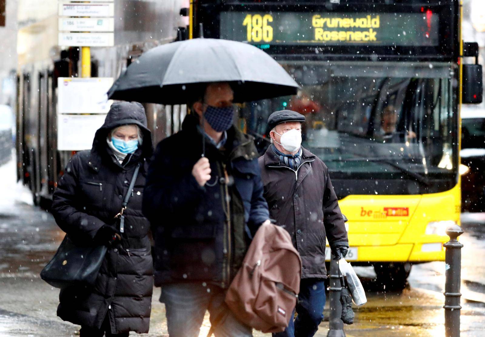 FILE PHOTO: People wear face masks as they walk past a bus in Berlin