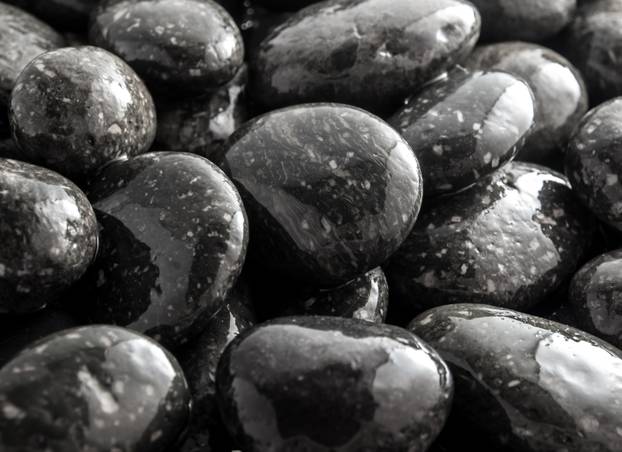 Round black stone on ground beside the waterfall