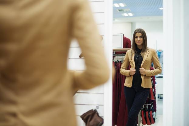 Beautiful,Young,Woman,Trying,On,Jacket,In,Front,Of,Mirror