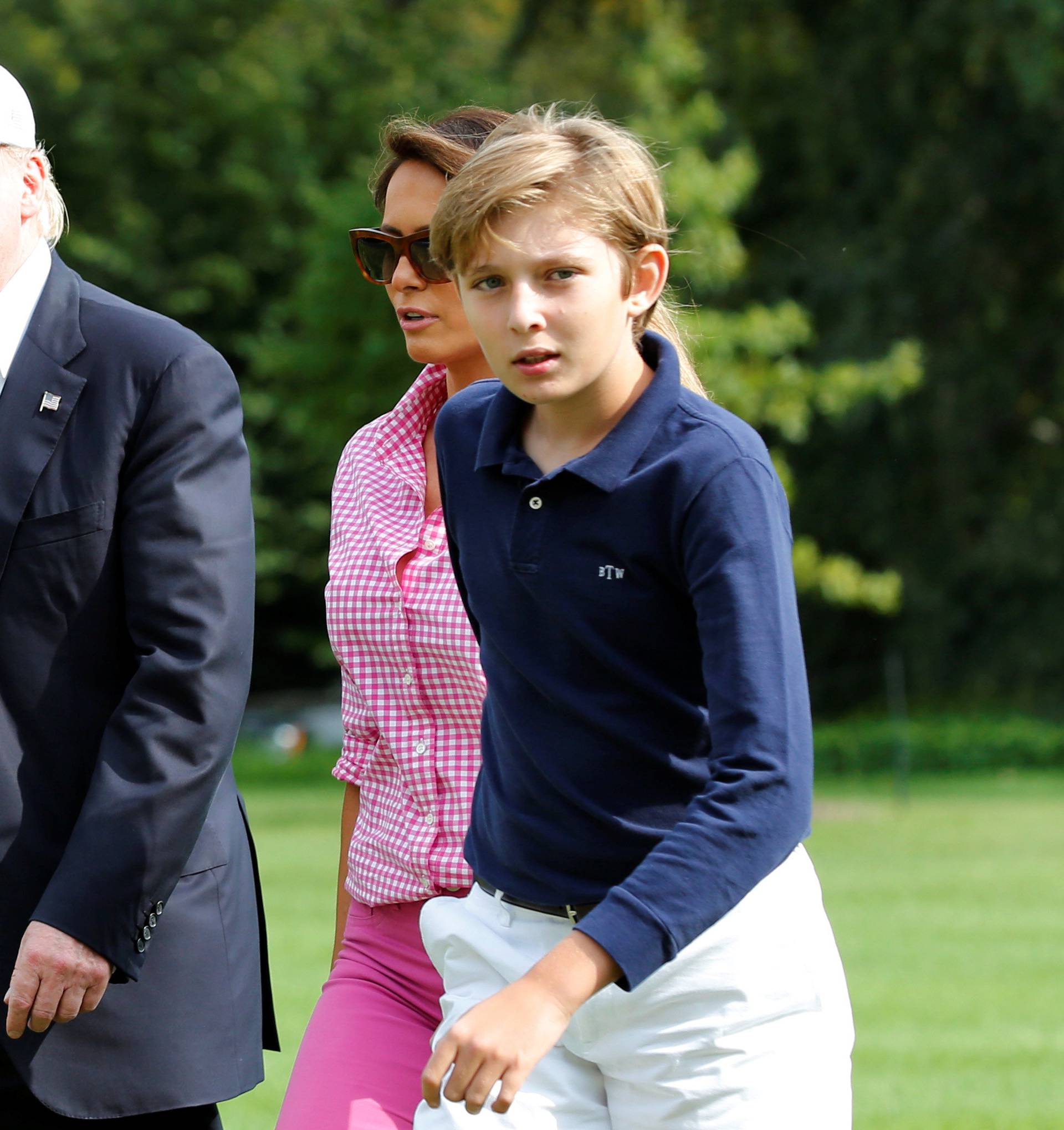 President Donald Trump waves as he with First Lady Melania Trump and their son Barron walk on South Lawn of the White House