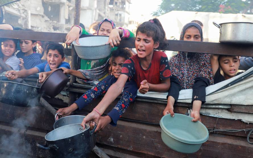 Palestinians wait to receive food from a charity kitchen amid hunger crisis, in Gaza City