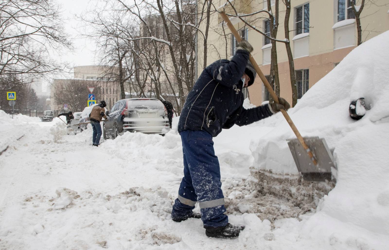 Workers remove snow in a street in Moscow