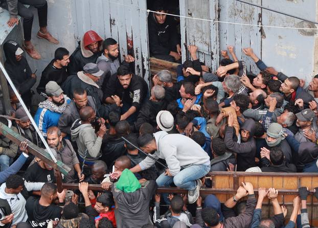 Palestinians gather to receive bread from a bakery in Deir Al-Balah