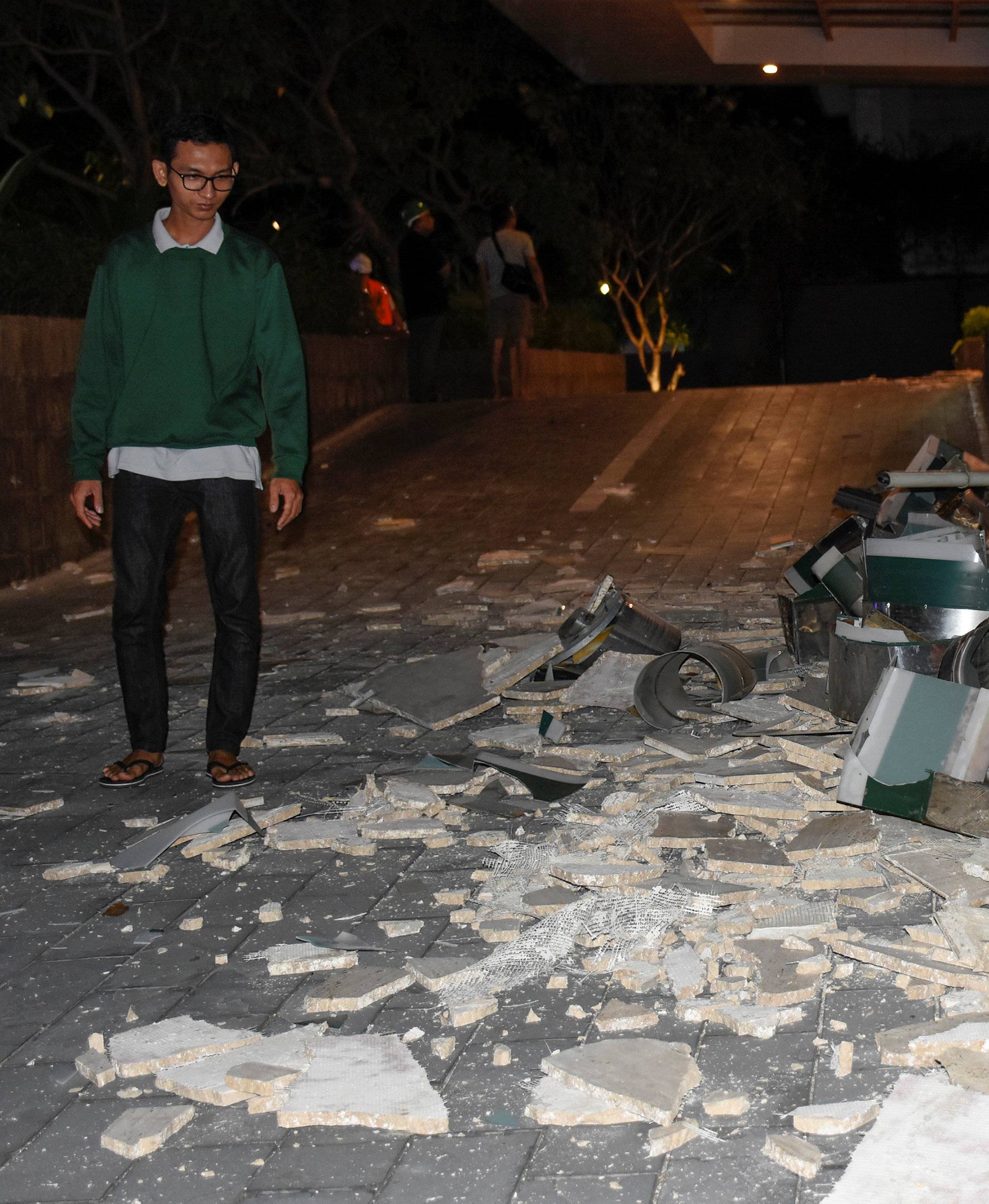 A man walks past debris which fell from a signboard outside the Santika hotel following a strong earthquake in Mataram,  Lombok island