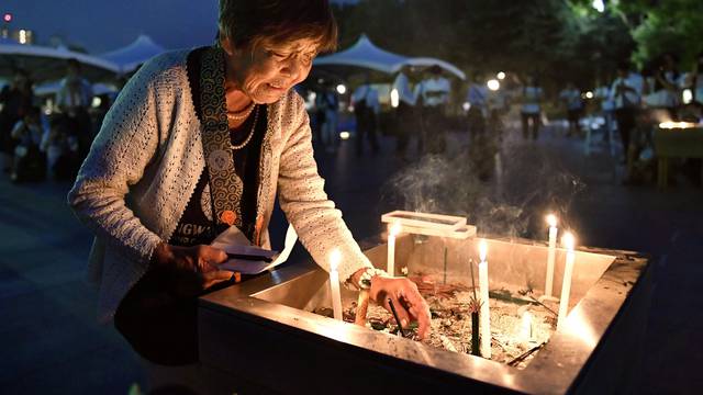 A woman lights up a candle in front of the cenotaph for the victims of the 1945 atomic bombing at Peace Memorial Park in Hiroshima