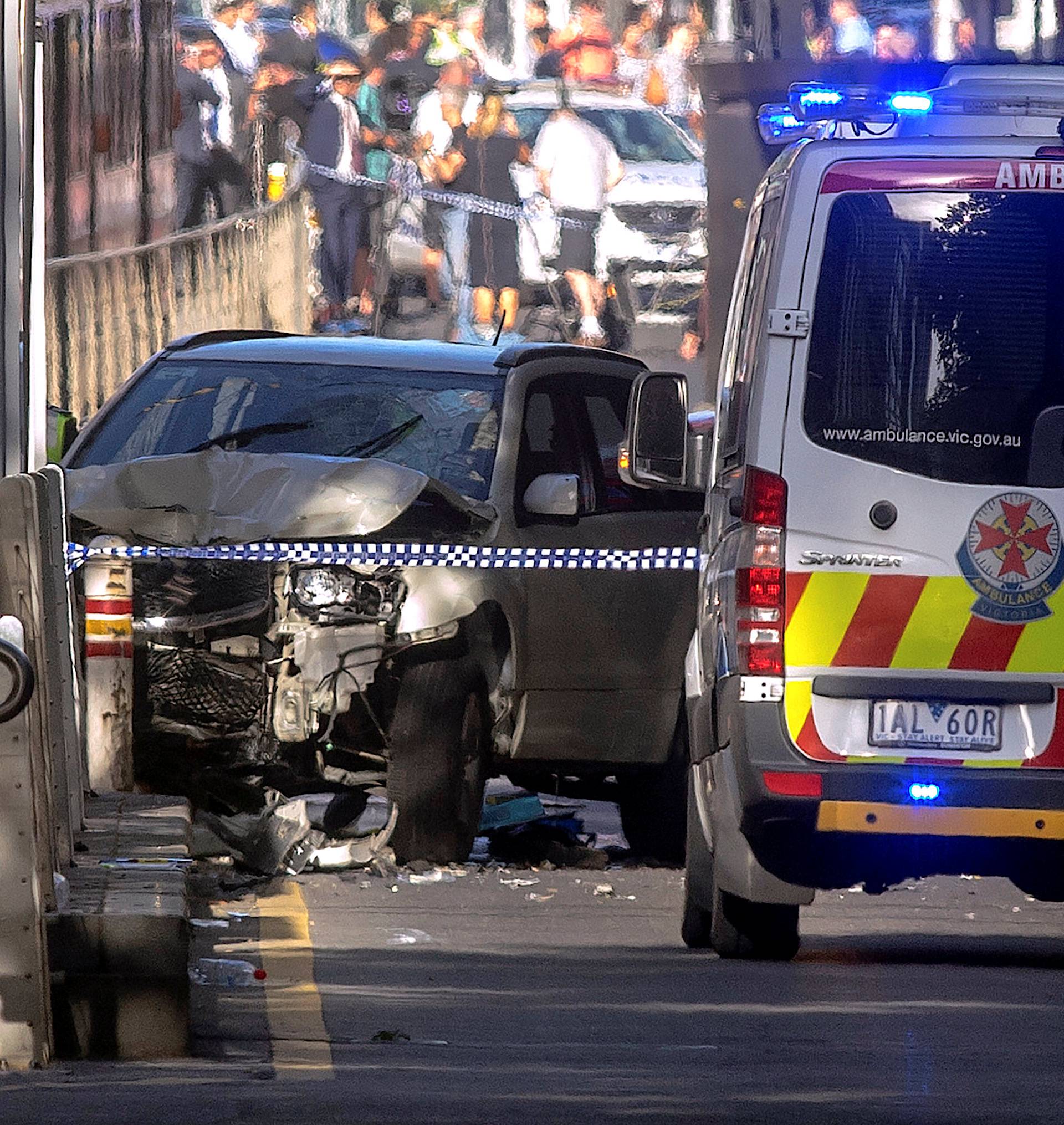 Australian police stand near a crashed vehicle after they arrested the driver of a vehicle that had ploughed into pedestrians at a crowded intersection near the Flinders Street train station in central Melbourne
