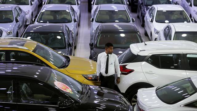 An auto dealer stands between the cars displayed for sale at a second hand car showroom Shoneez Motors in Sanabis, west of Manama