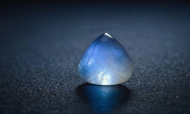 Natural precious moonstone on a gray background. Natural stone adularia