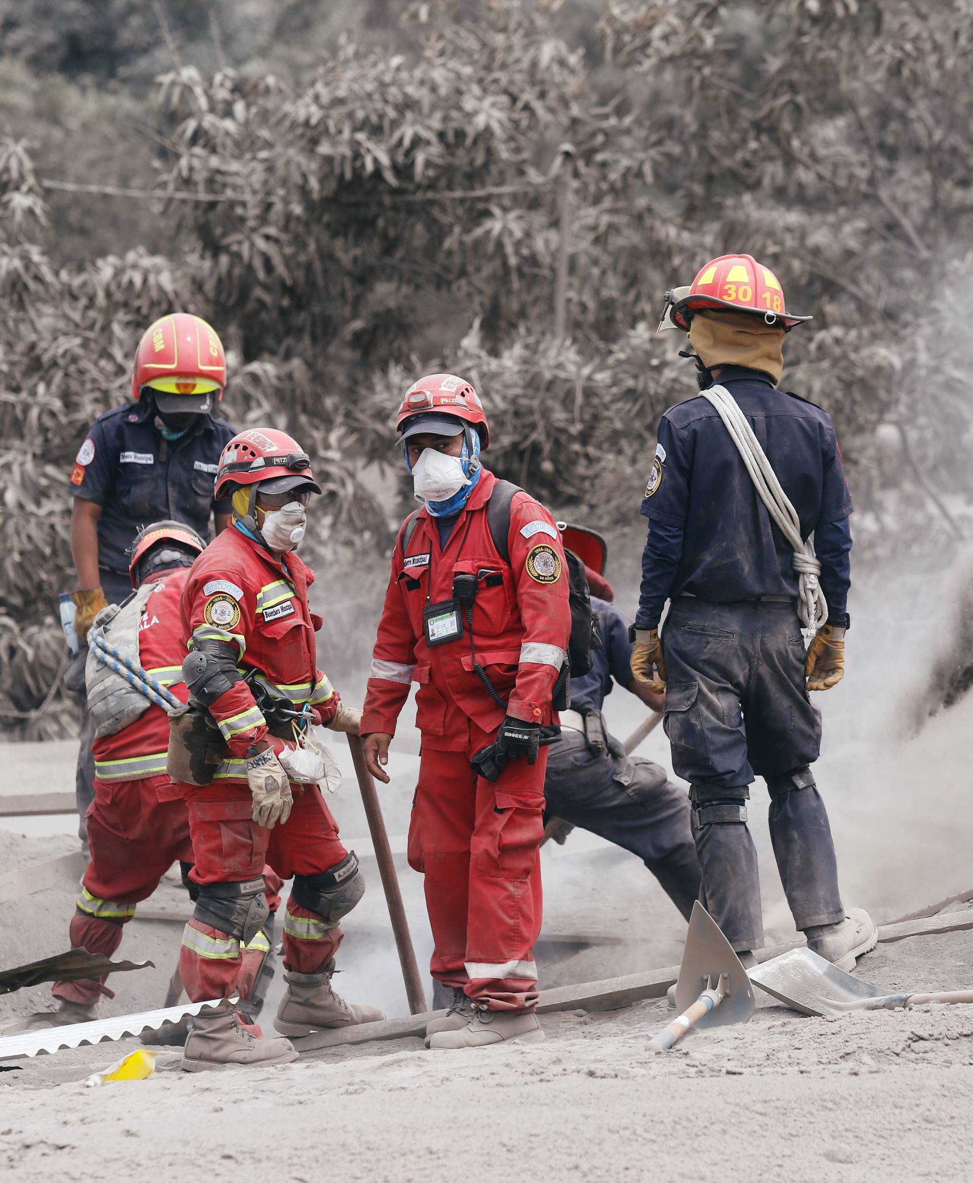 Rescue workers remove ash at an area affected by the eruption of the Fuego volcano in the community of San Miguel Los Lotes in Escuintla