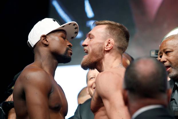 Undefeated boxer Floyd Mayweather Jr. (L) of the U.S. and UFC lightweight champion Conor McGregor of Ireland face off during their official weigh-in at T-Mobile Arena in Las Vegas