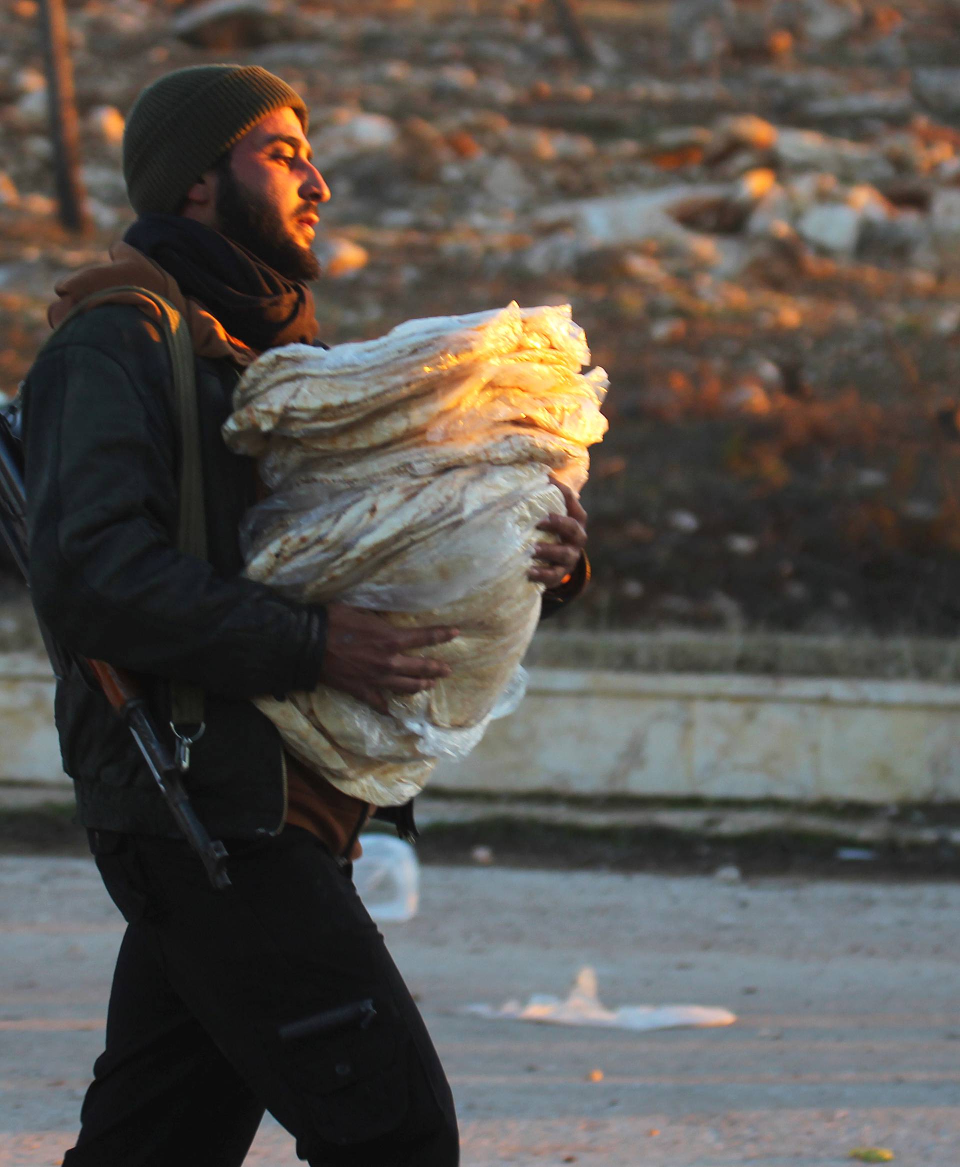 A rebel fighter carries bread for evacuees from rebel-held east Aleppo, upon their arrival to the town of al-Rashideen