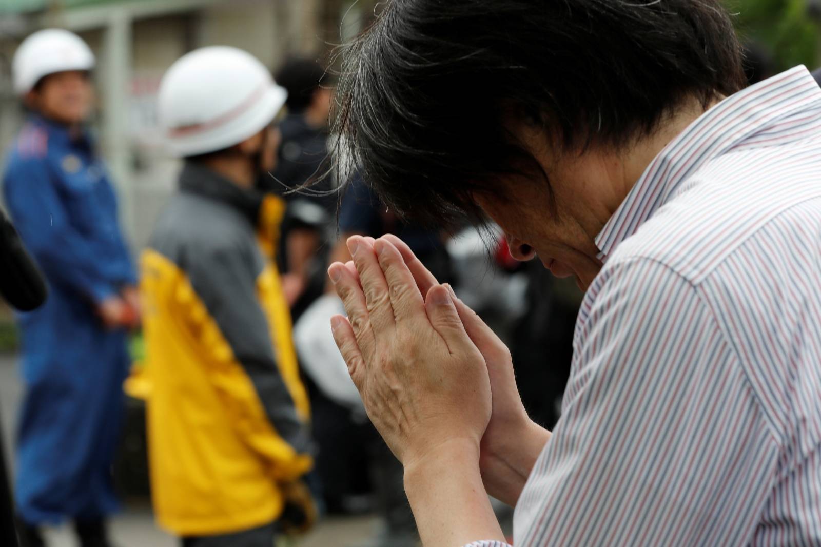 A man prays for the victims of the arson attack near the torced Kyoto Animation building n Kyoto