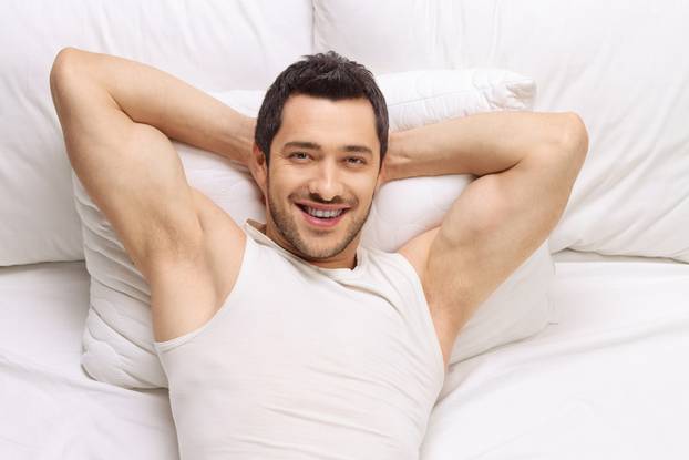 Young man lying in a bed and smiling