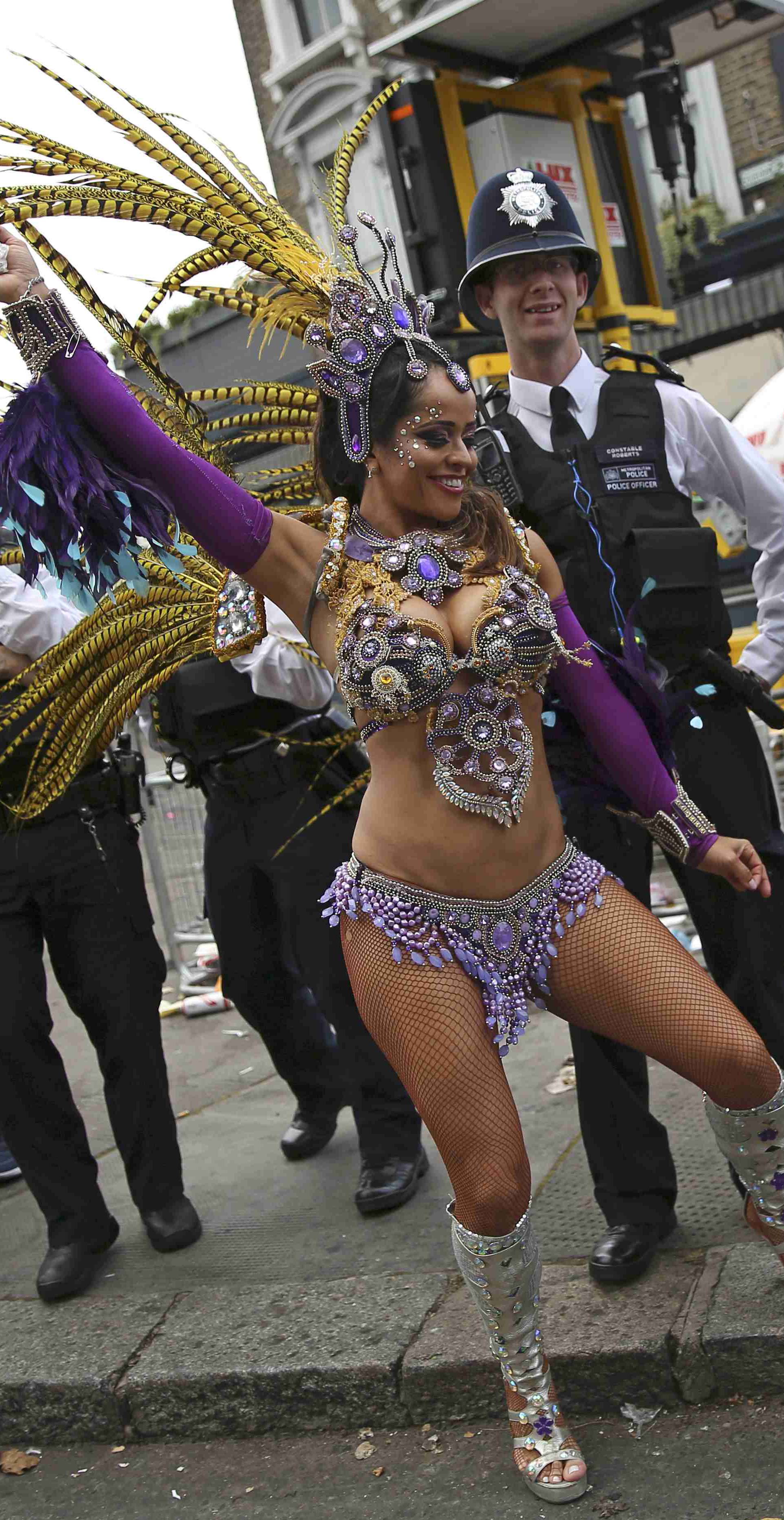 Police look as a performer dances during the Notting Hill Carnival in London