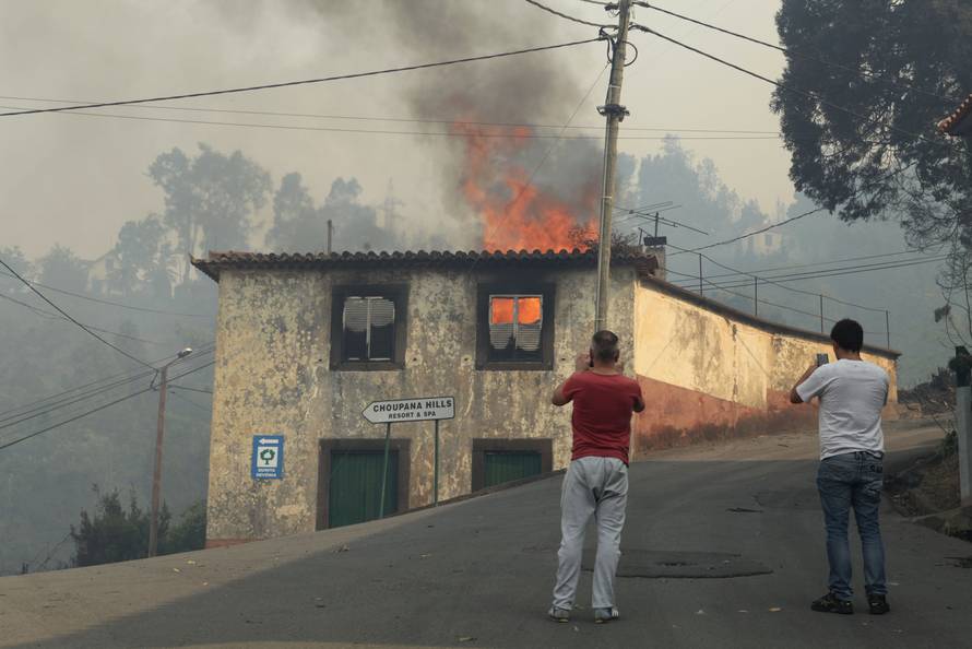Men take pictures of a burning house at Caminho do Meio during the forest fires in Funchal
